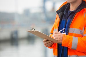 Man in hi-vis orange jacket, holding a clipboard | Maritime Training with the Maritime Skills Academy