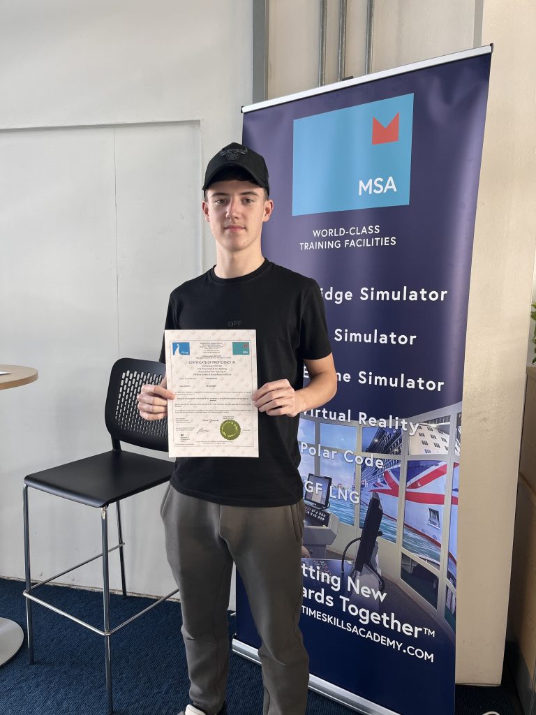 Delegate Finn Reeves stood holding his certificate after completing his STCW Basic Safety Training Week at MSA Dover