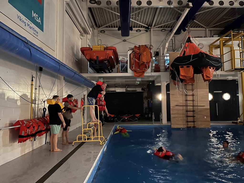 Paul Watts preparing to jump from a 1m height on the side of the pool with a life jacket on | MSA Dover STCW Basic Safety Training Week